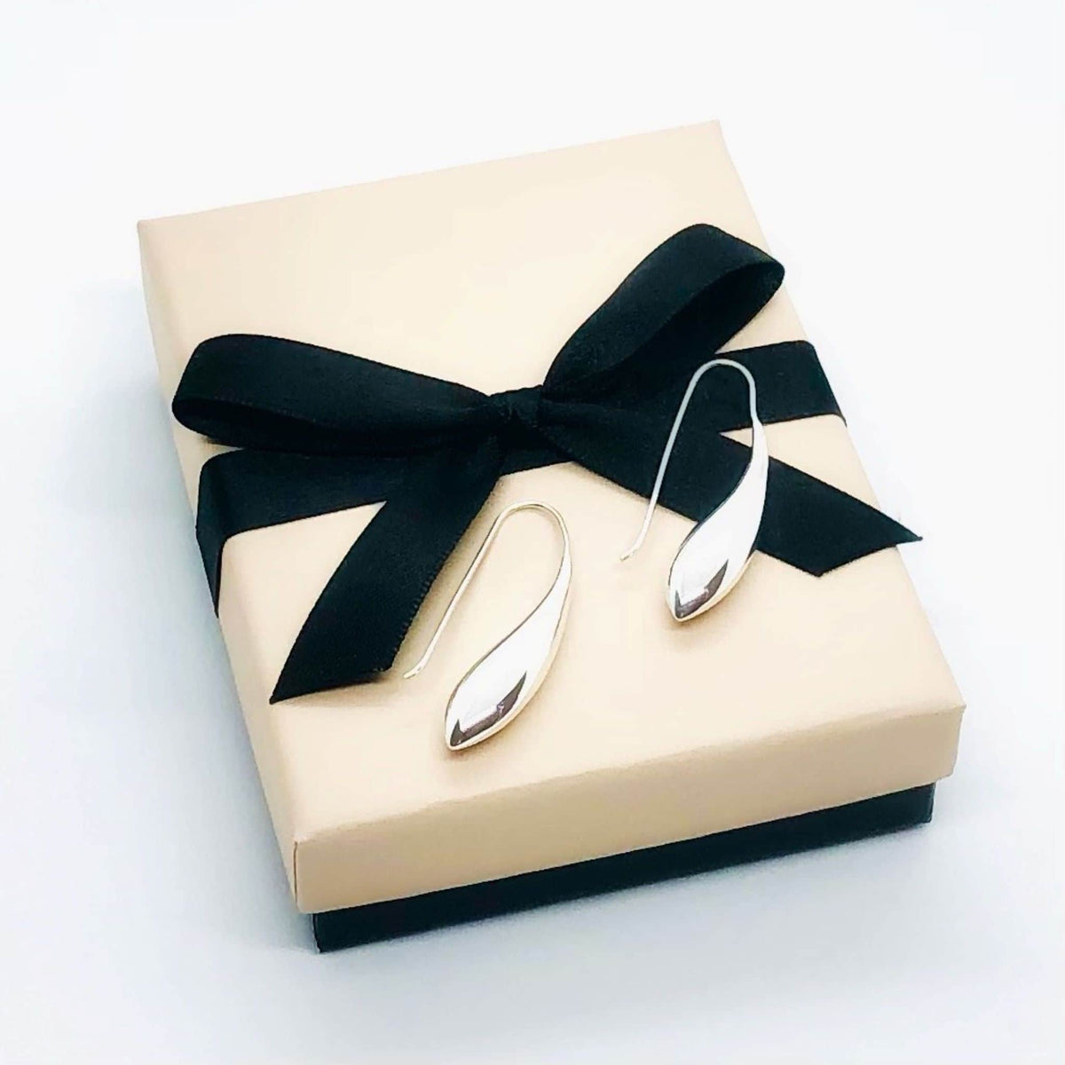 Sterling silver teardop earrings with shepherd hook fixture. Smooth fluid lines accentuate the teardrop shape. High polish finish. Comes in its own taupe coloured box with black gloss base and finished with black grosgrain bow.